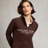 Woman wearing a brown Holland Cooper sweatshirt against a neutral background
